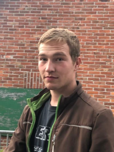 Porträt eines jungen Mannes vor einer Backsteinwand