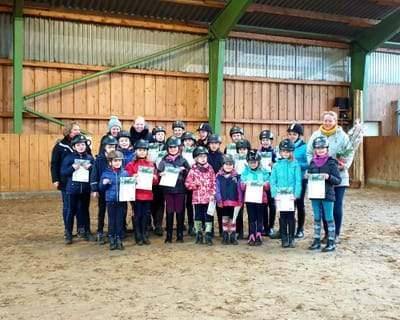Reitschülerinnen und Reitschüler mit Urkunden nach der Reitabzeichenprüfung in der Reithalle